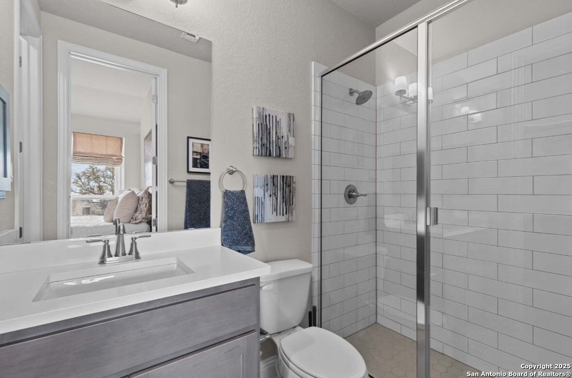 Modern master bathroom with frameless glass shower, white subway tiles, and sleek gray vanity in Davidson Homes Garner B, Ladera San Antonio