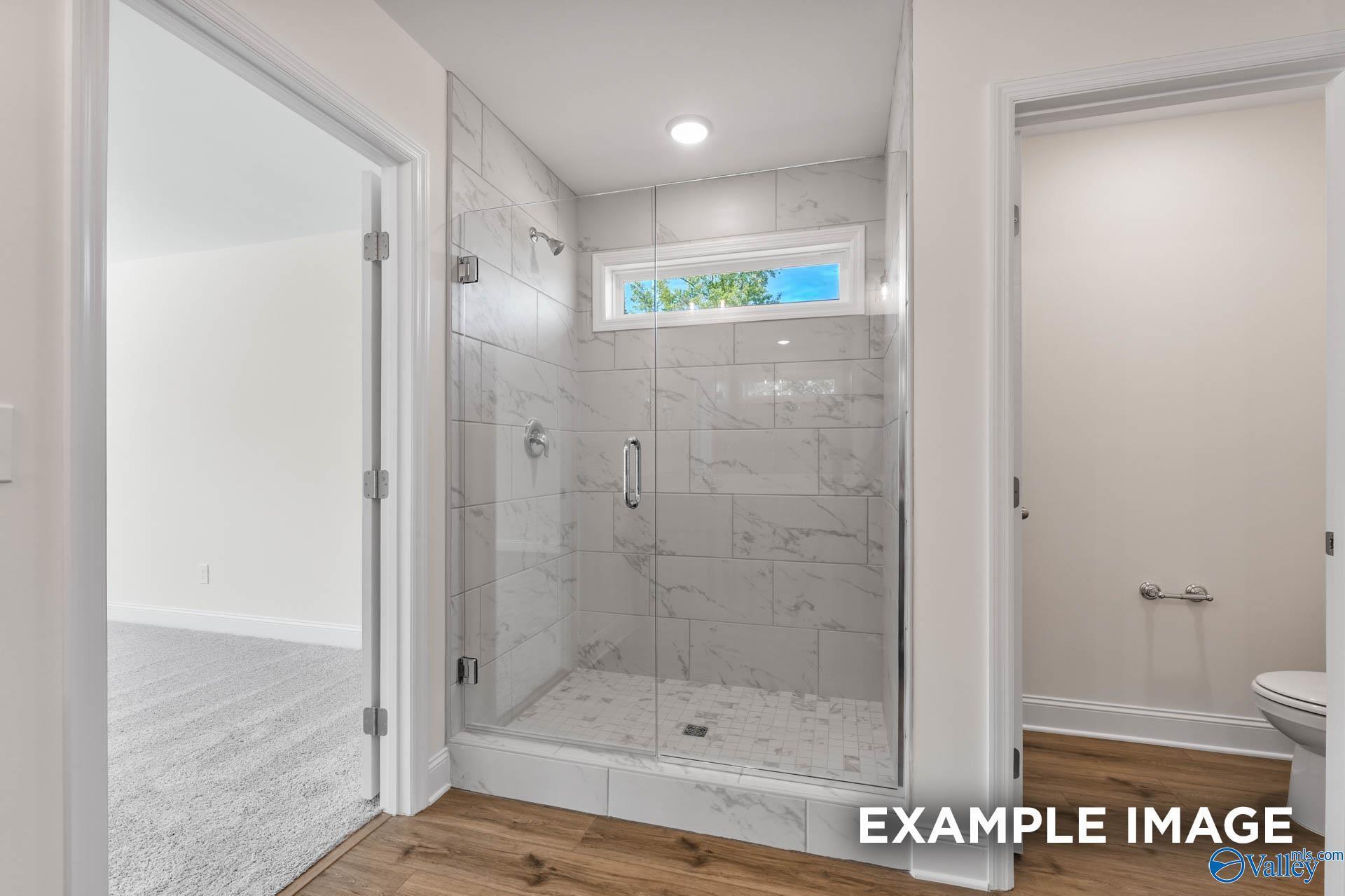 Modern master bathroom with frameless glass shower, subway tile walls, and frosted window in Davidson Homes The Shelby A, Hazel Green, AL