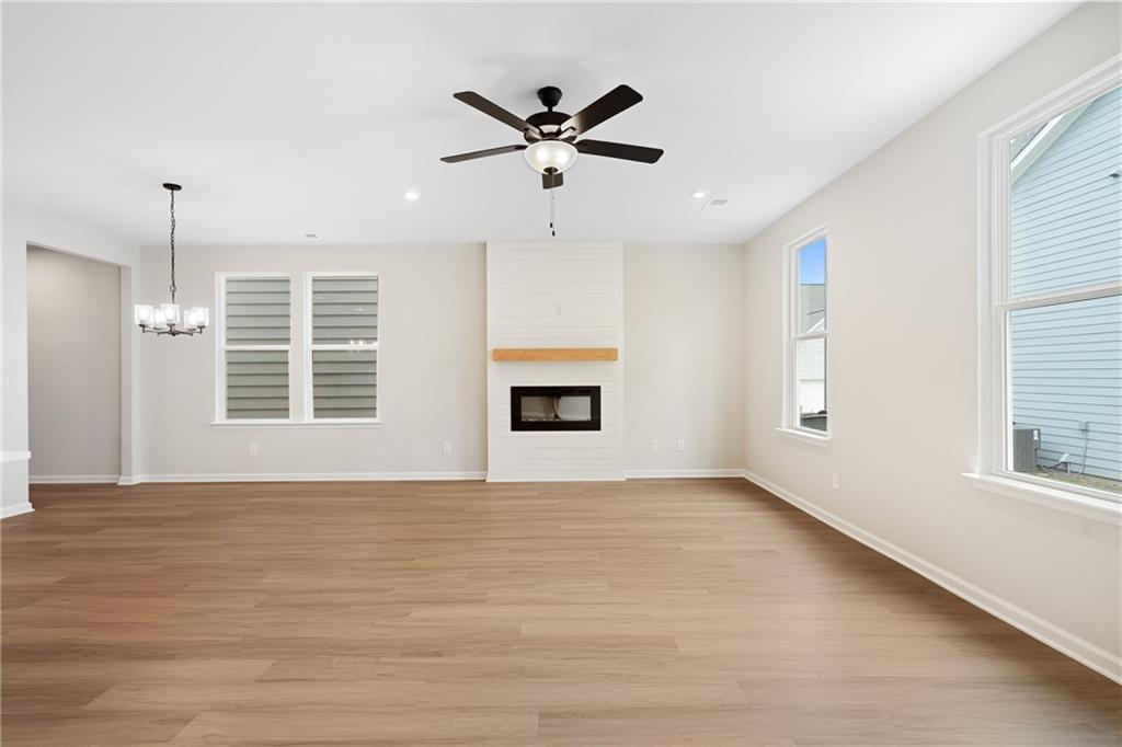 Cozy family room with gas fireplace, hardwood floors, ceiling fan, and shuttered windows in Davidson Homes The Marion A, Kennesaw GA