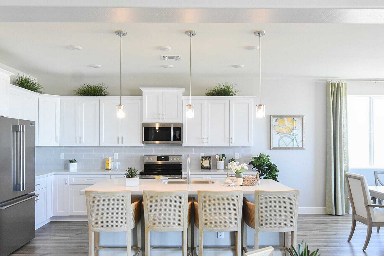 Spacious white kitchen in The Summit B with shaker cabinets, stainless appliances, large island, and adjacent dining area