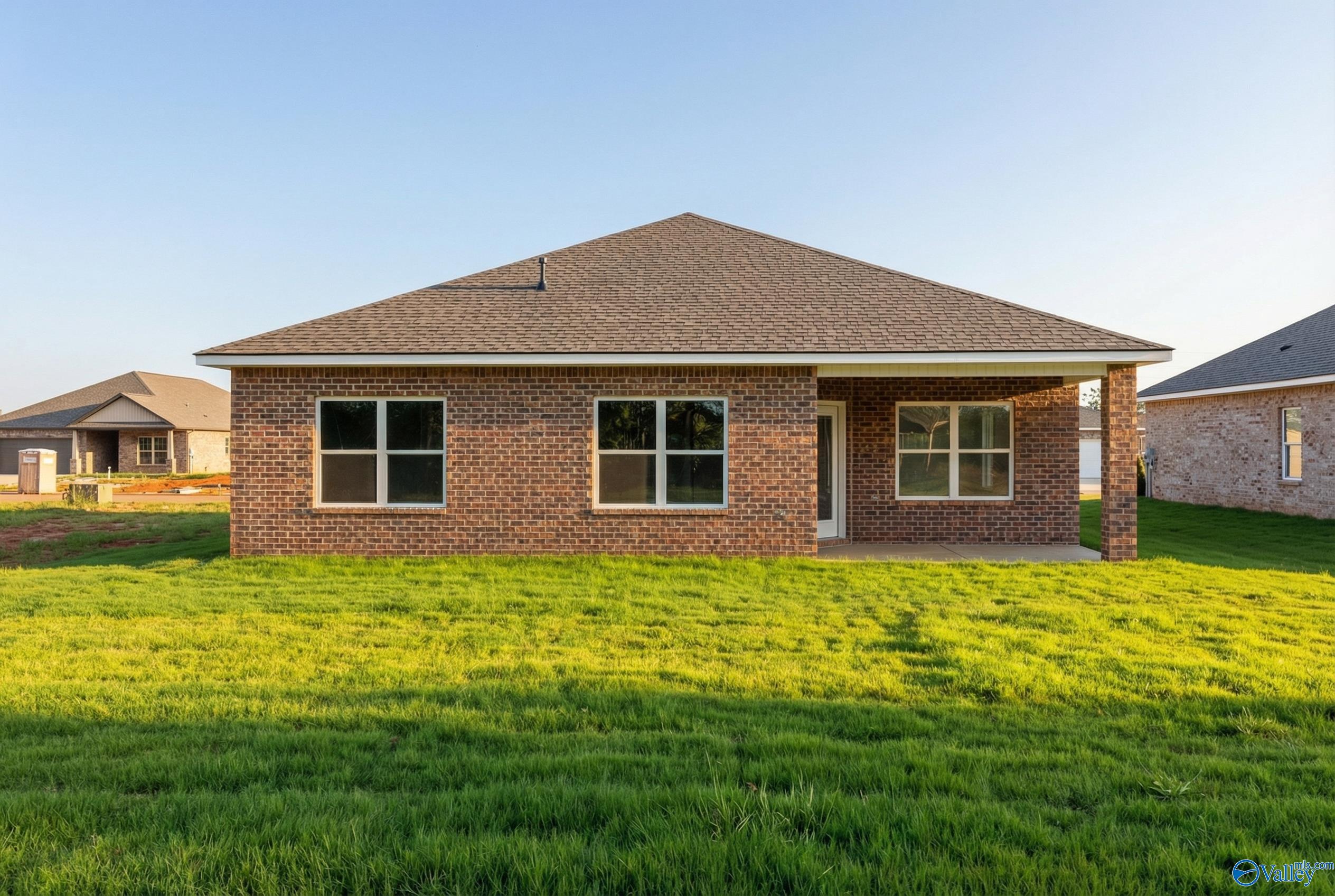 Single-story brick home with gabled roof, large windows, and front door on lush green lawn in Lynn Meadows, Meridianville, Alabama
