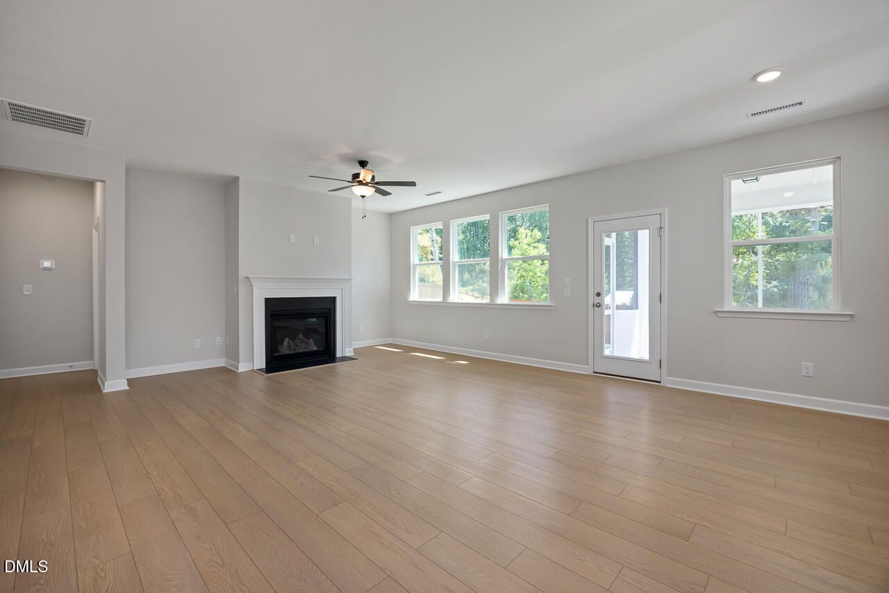 Spacious living room with fireplace and light wood floors in The Ashport L plan at Sage on North Main, Wake Forest, NC.