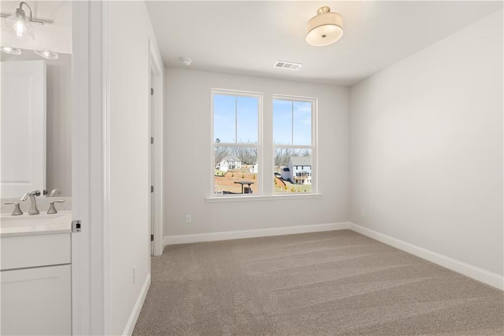 Bright bedroom with en-suite bathroom, large windows overlooking neighborhood in Davidson Homes The Danbury C, Buford, GA