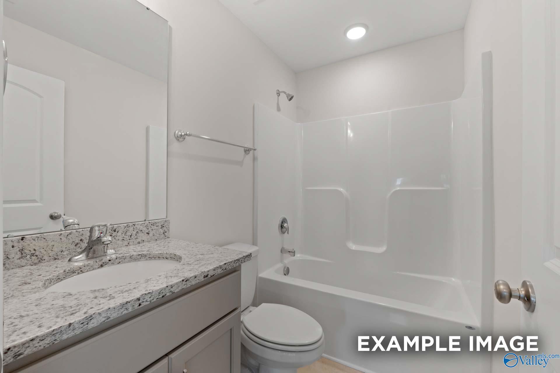 Contemporary bathroom with granite vanity, white tub-shower combo, and fixtures in Davidson Homes Madison A, Toney, Alabama