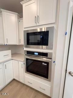 Built-in stainless steel oven and microwave in modern white kitchen at The Daphne D floor plan in Zebulon, North Carolina.