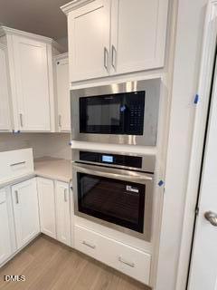 Built-in stainless steel oven and microwave in modern white kitchen at The Daphne D floor plan in Zebulon, North Carolina.