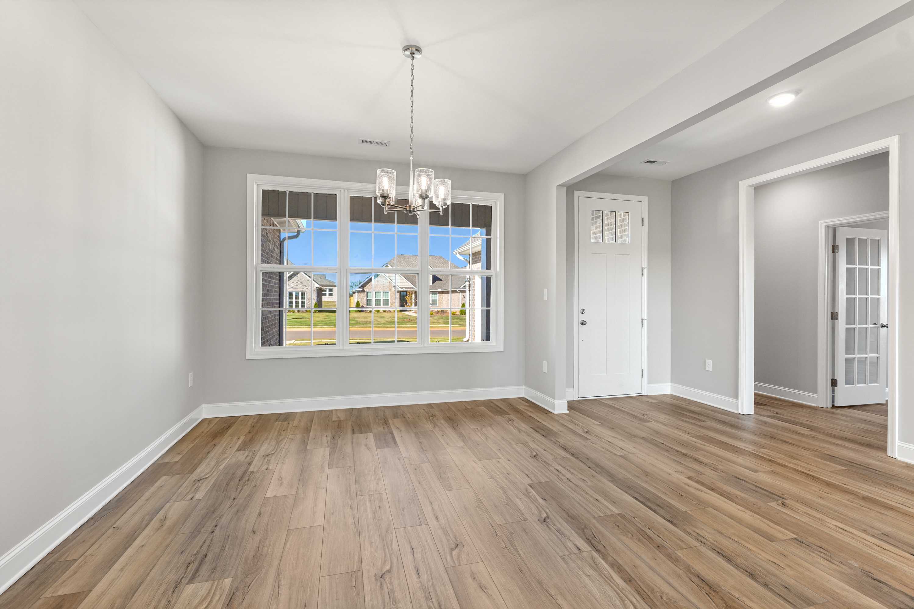 Spacious living room in The Valencia Davidson home with large window views, hardwood floors, and chandelier lighting
