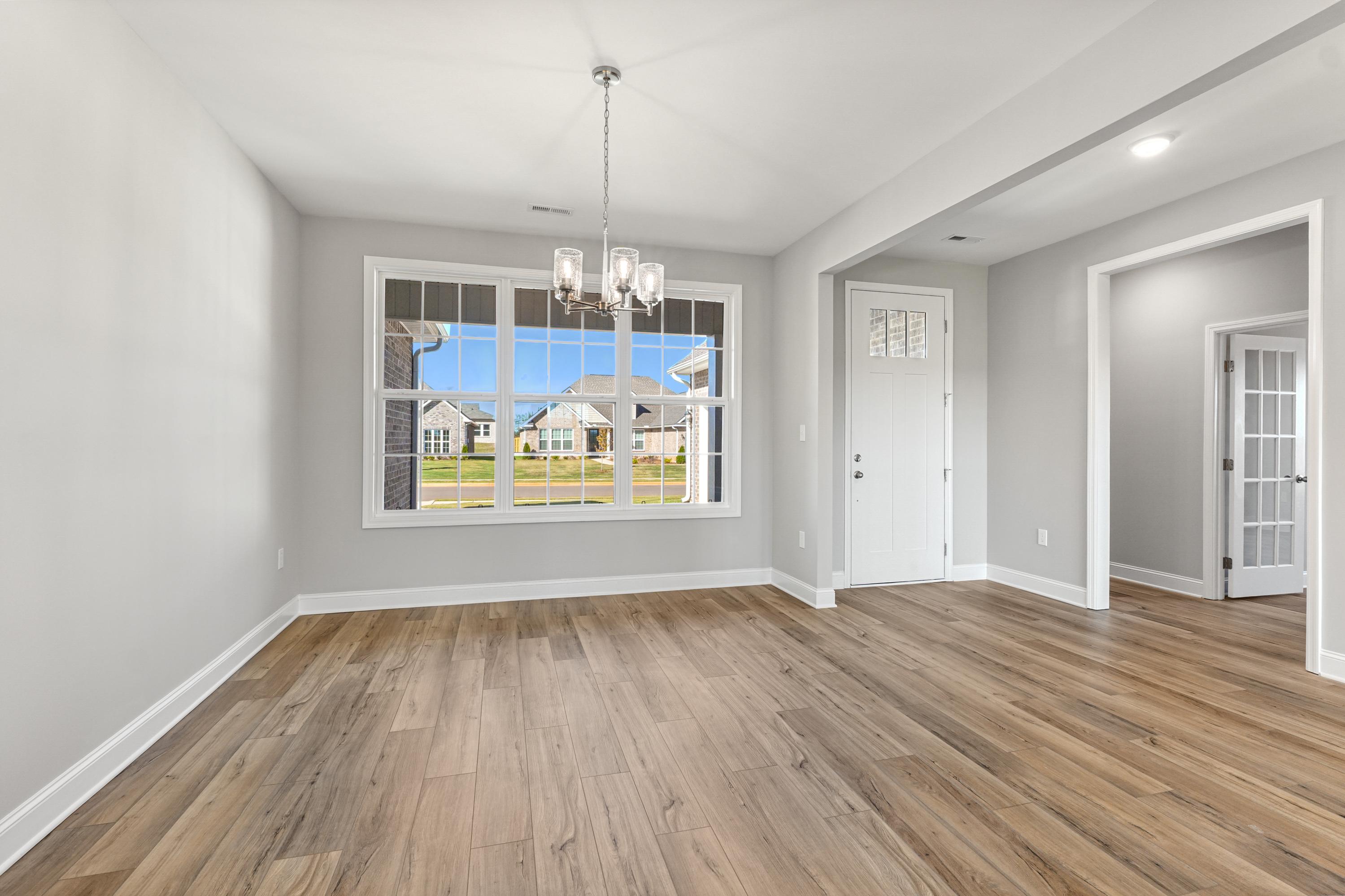 Spacious living room in The Valencia Davidson home with large window views, hardwood floors, and chandelier lighting