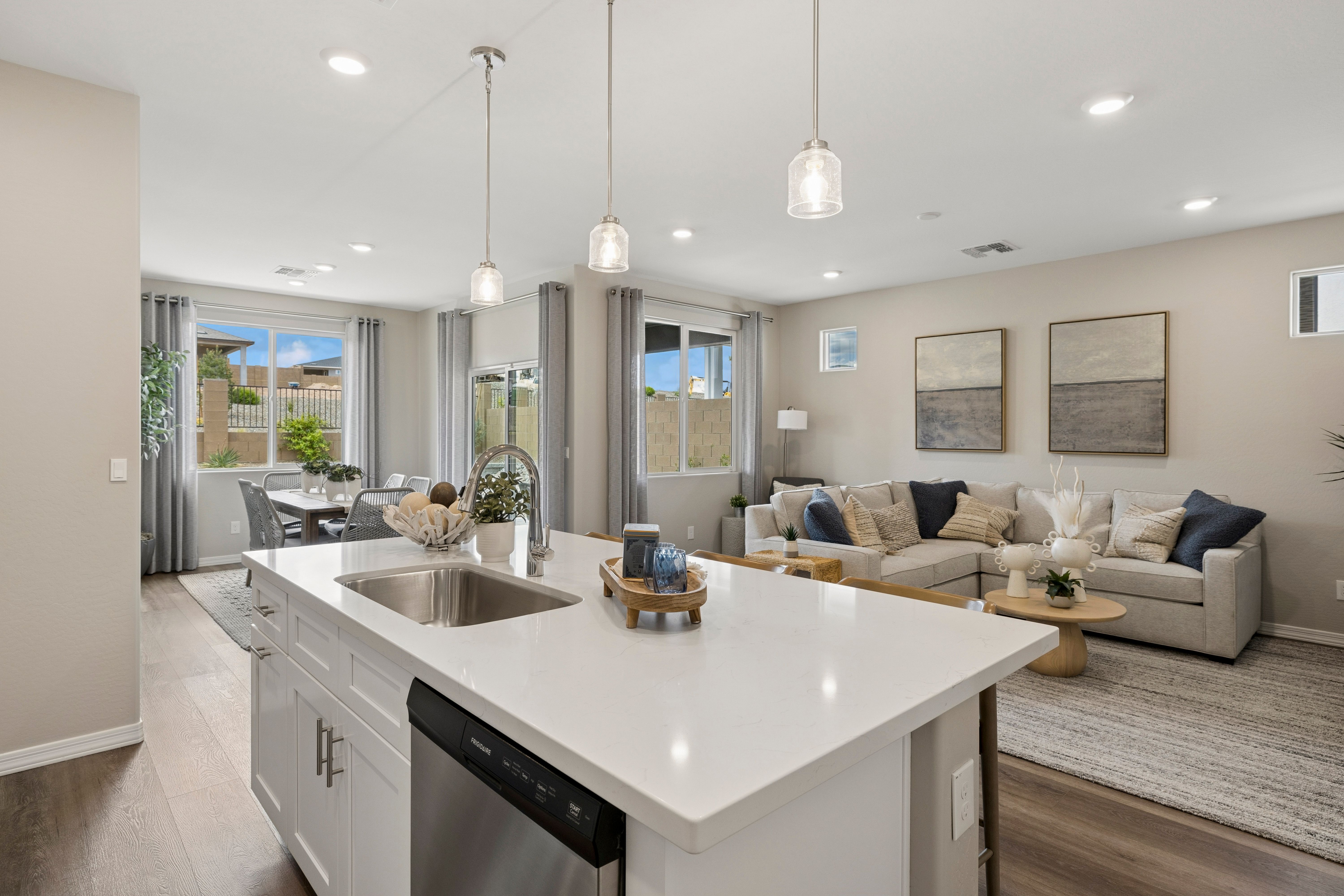 Open-concept kitchen and living area at South Ranch Destination Collection in Prescott AZ with white quartz island, pendant lights, and neutral decor