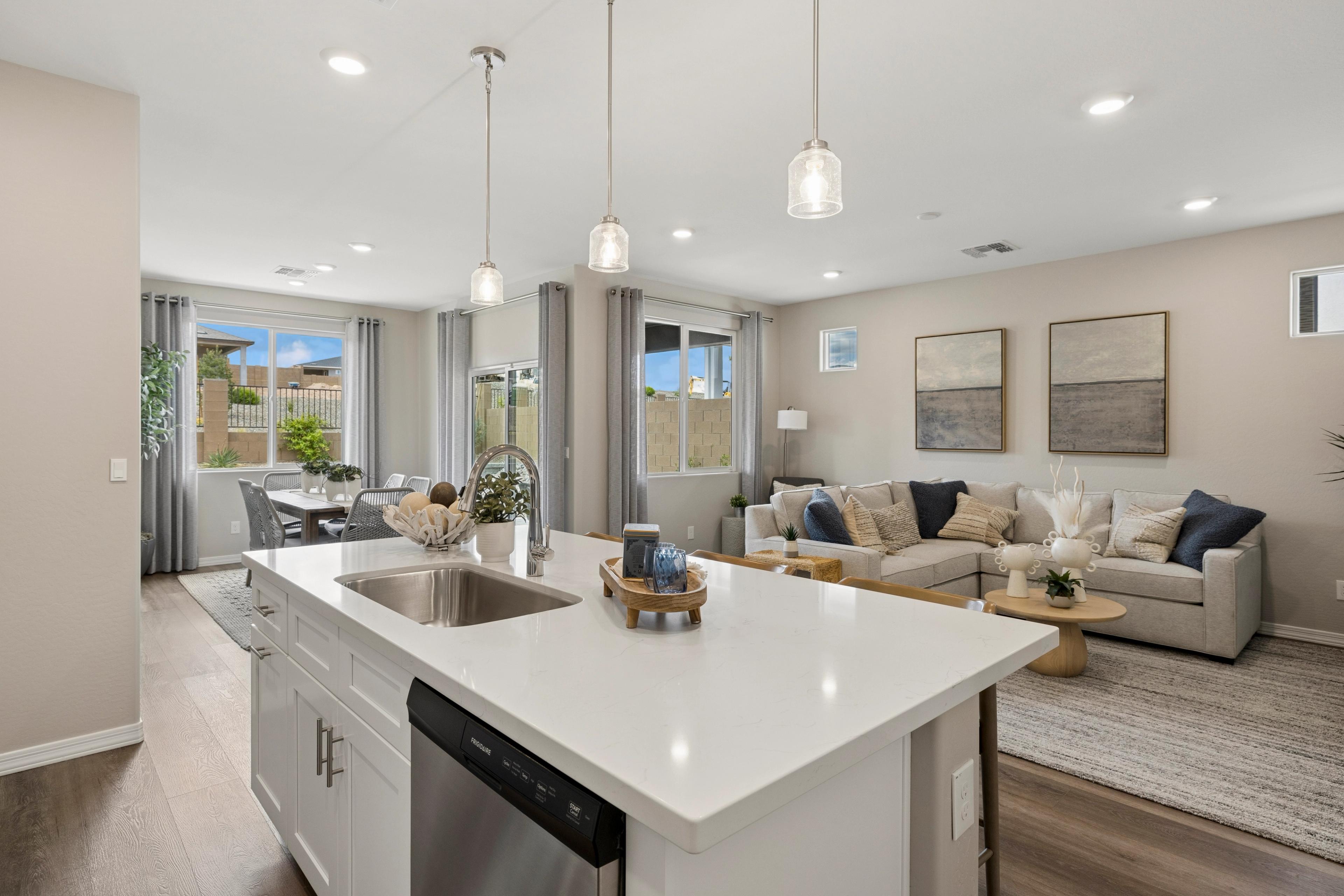 Open-concept kitchen and living area at South Ranch Destination Collection in Prescott AZ with white quartz island, pendant lights, and neutral decor