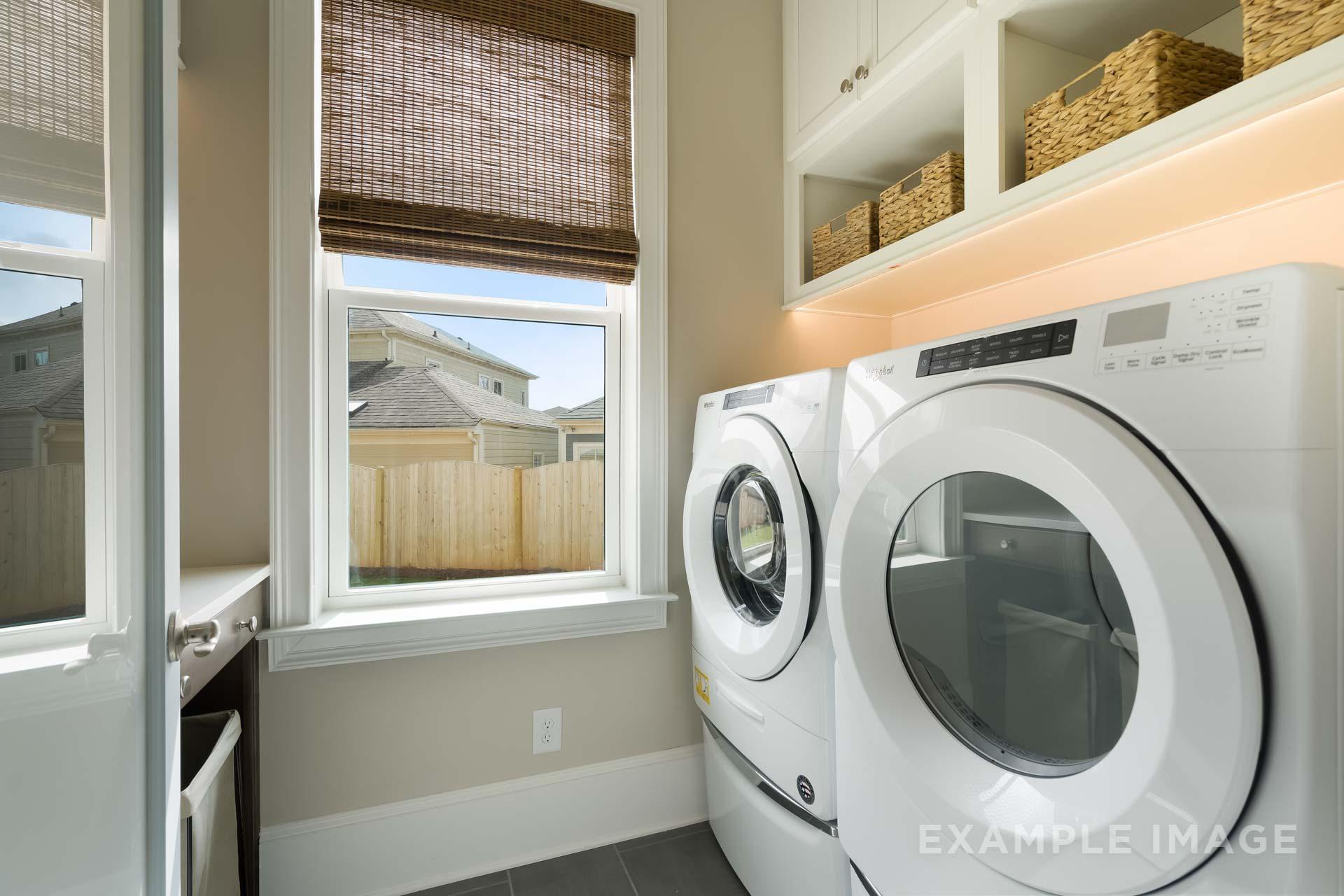 Bright laundry room in The Seaside Davidson Homes design with side-by-side white washer dryer, bamboo blinds, and wicker shelves