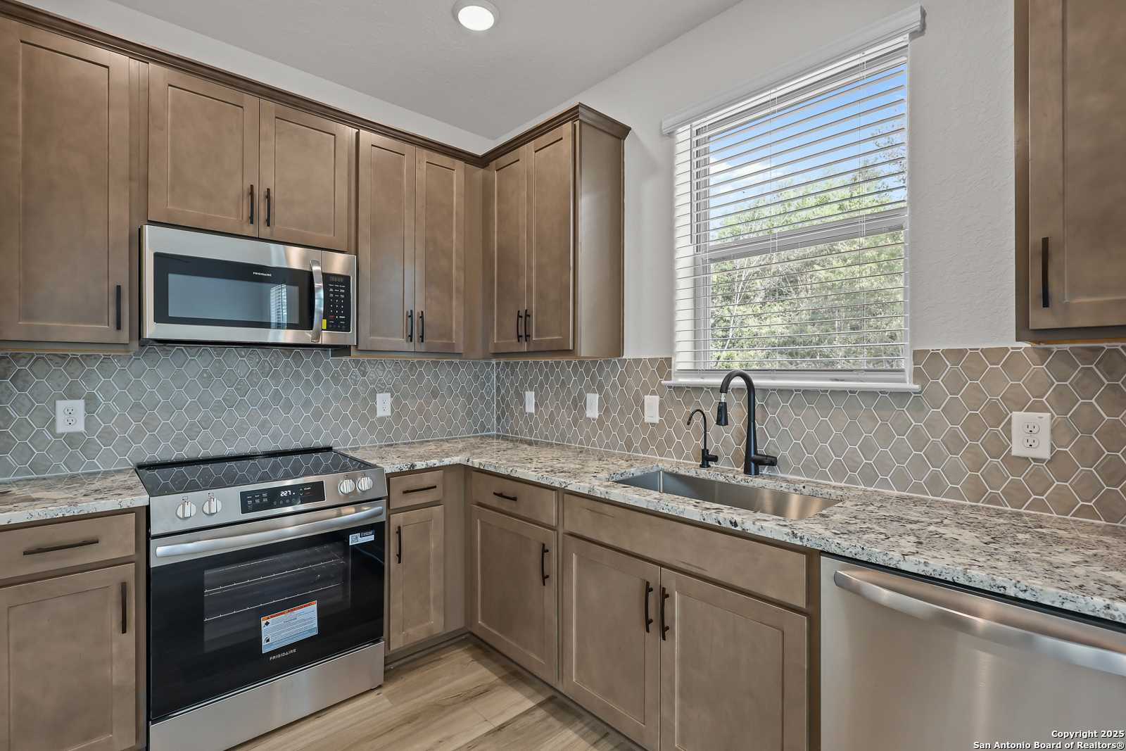 Contemporary kitchen with shaker cabinets, stainless steel appliances, quartz counters, and patterned tile backsplash in Davidson Homes The Florence C, San Antonio