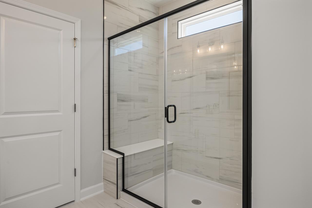Modern walk-in shower with marble-look tile and black trim in The Birch II master suite by Davidson Homes.