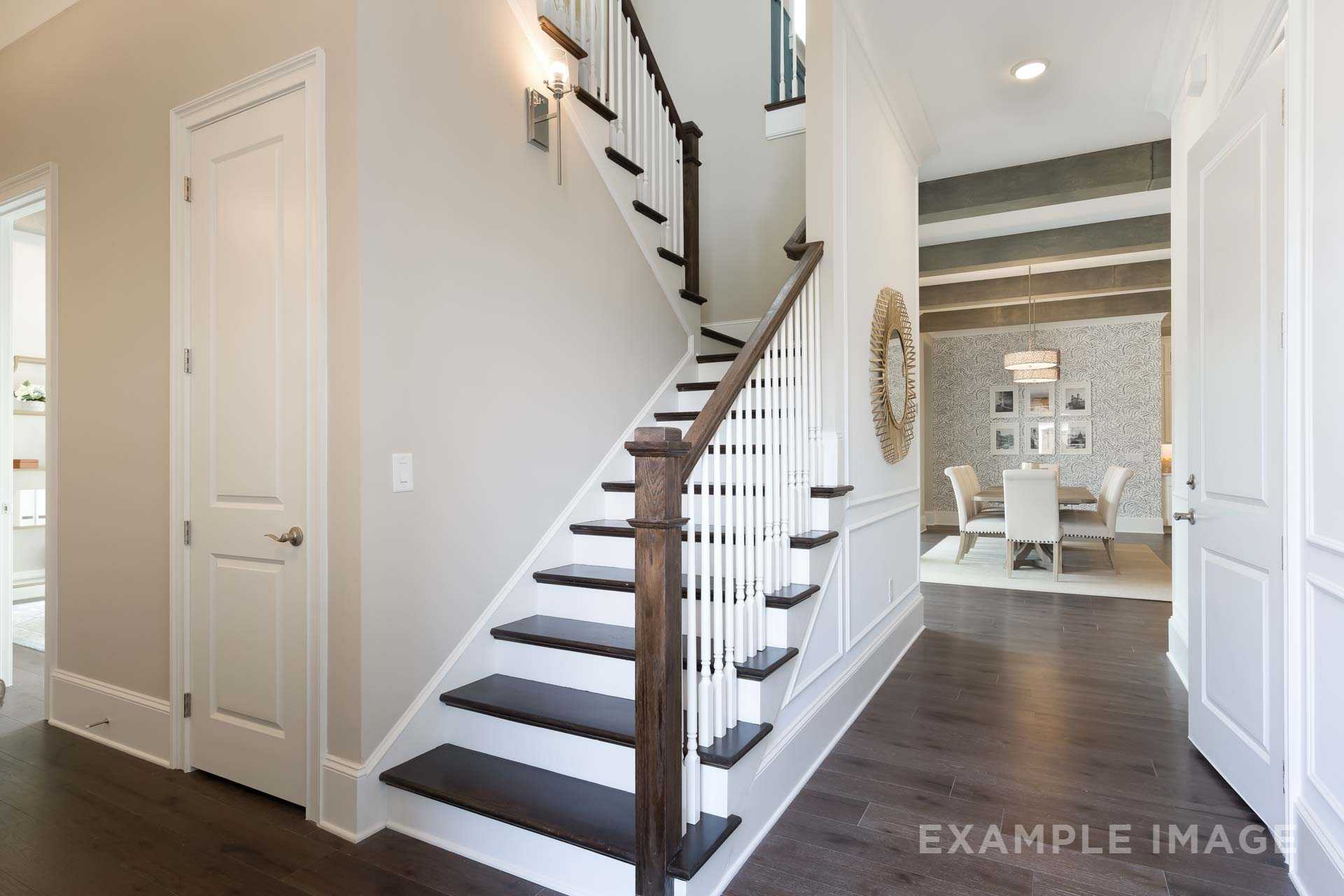 Spacious foyer in The Seaside B with grand wooden staircase, white balusters, and adjacent dining room