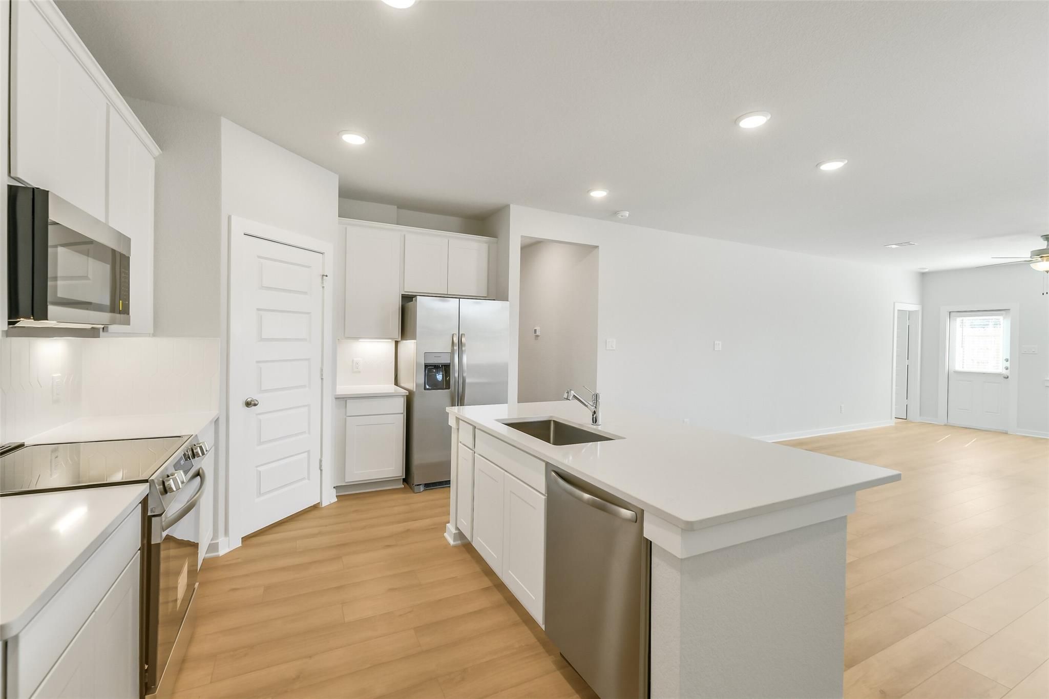 Modern kitchen with white cabinets, stainless steel appliances, and large island in Davidson Homes The San Marcos E, Cleveland, Texas