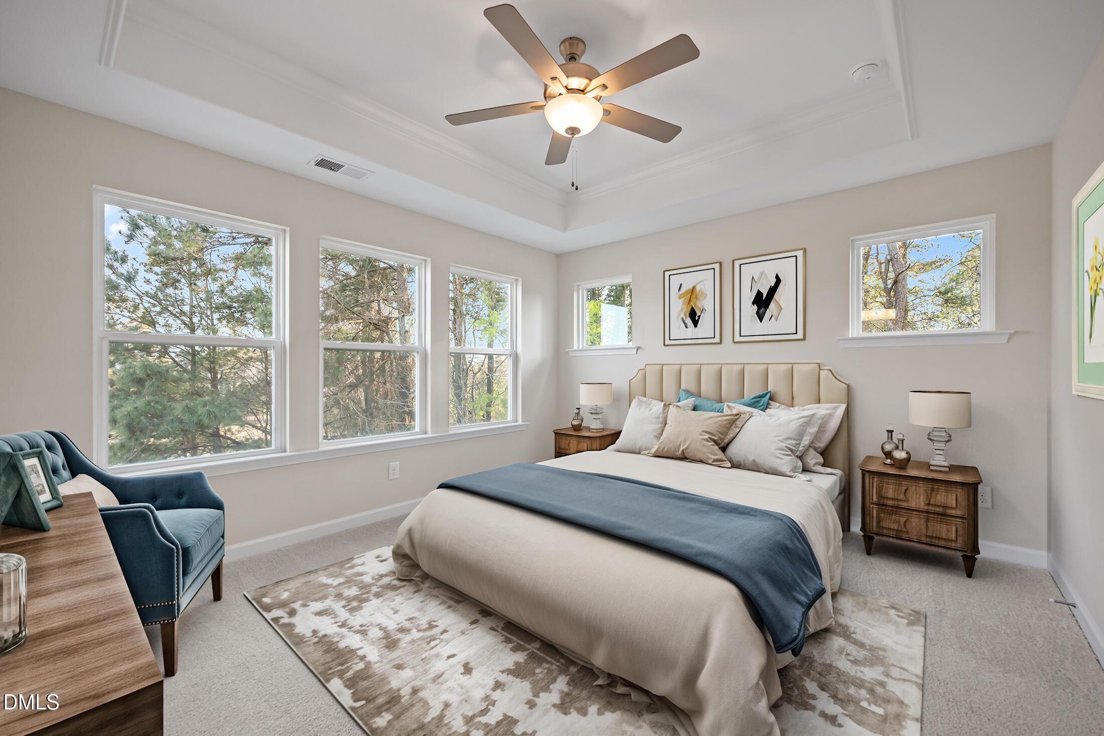 Bright master bedroom with king bed, velvet armchair, ceiling fan, and tree-view windows in Davidson Homes The Avery, Knightdale, NC