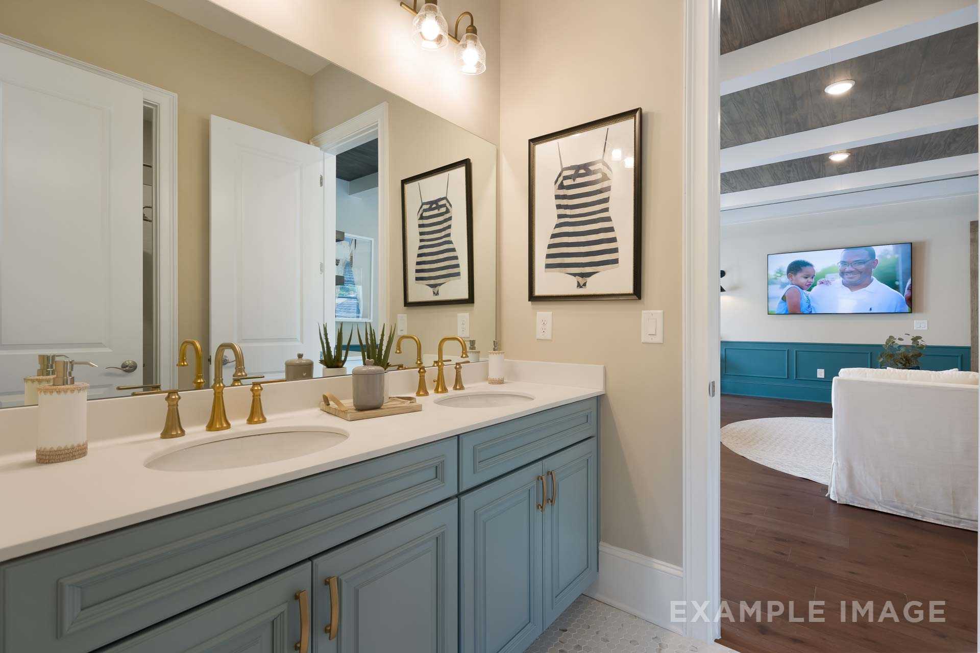Spacious master bathroom in The Seaside featuring double quartz vanity, blue cabinets, gold faucets, and adjacent sitting area