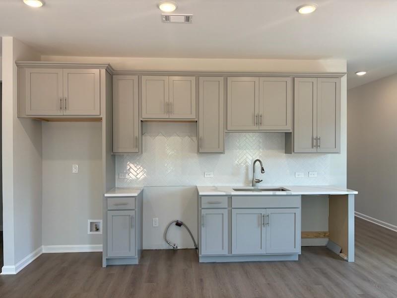 Modern gray shaker kitchen with herringbone subway tile backsplash, quartz counters, and pull-down faucet in Davidson Homes The Rabun A, Winder, GA