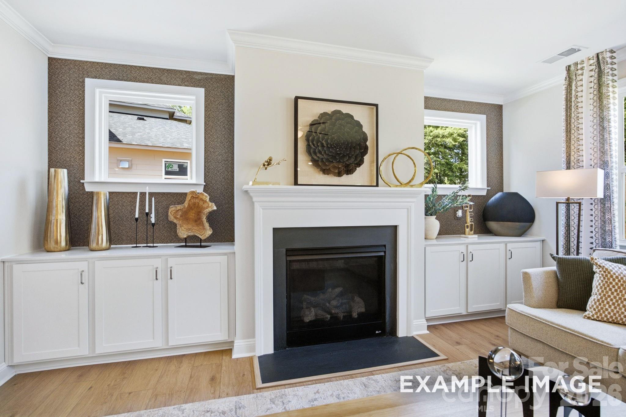Living room fireplace with built-in white cabinets and patterned wallpaper in The Hickory B II home at Windgate, Mooresville.