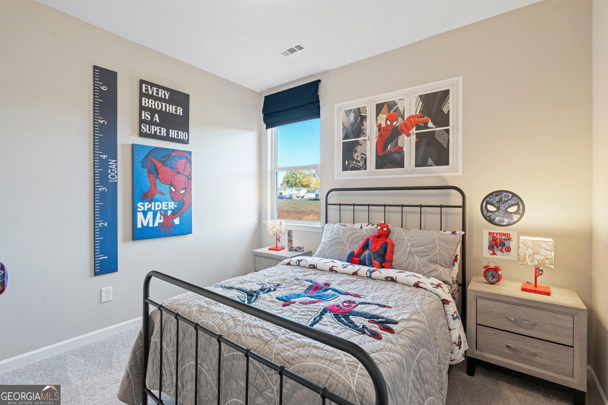 Cozy Spider-Man themed kids' bedroom with twin bed, posters, height chart, and beige walls in Evermore Homes The Phoenix, Perry, Georgia