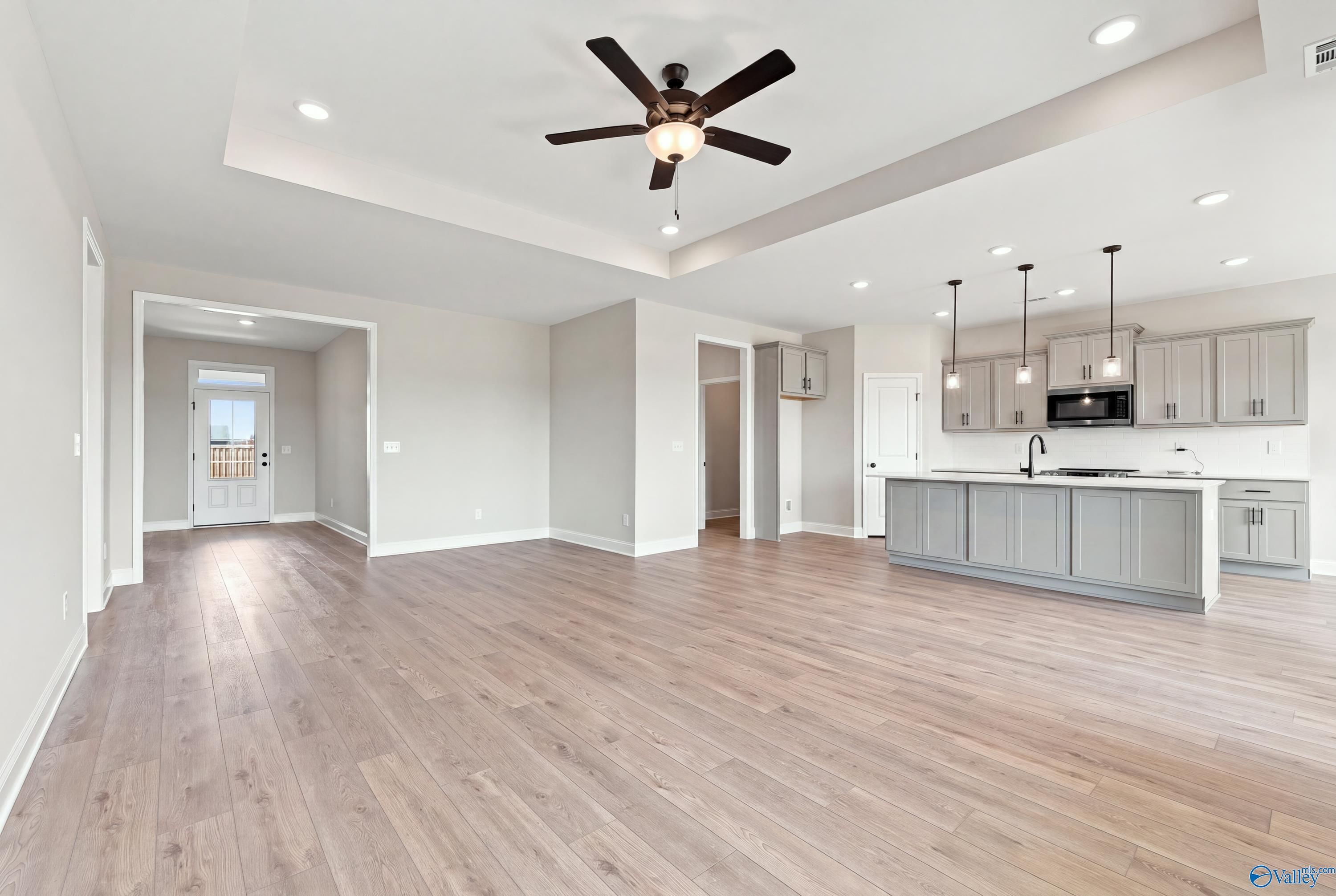 Open-concept living area with tray ceiling, ceiling fan, and kitchen island in Davidson Homes The Montgomery D, Athens, Alabama