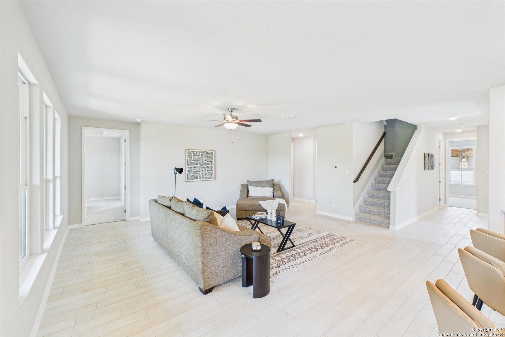 Spacious living room with beige sectional sofa, ceiling fan, staircase, and dining nook in The Jennings H 5-bedroom home, Ladera, San Antonio