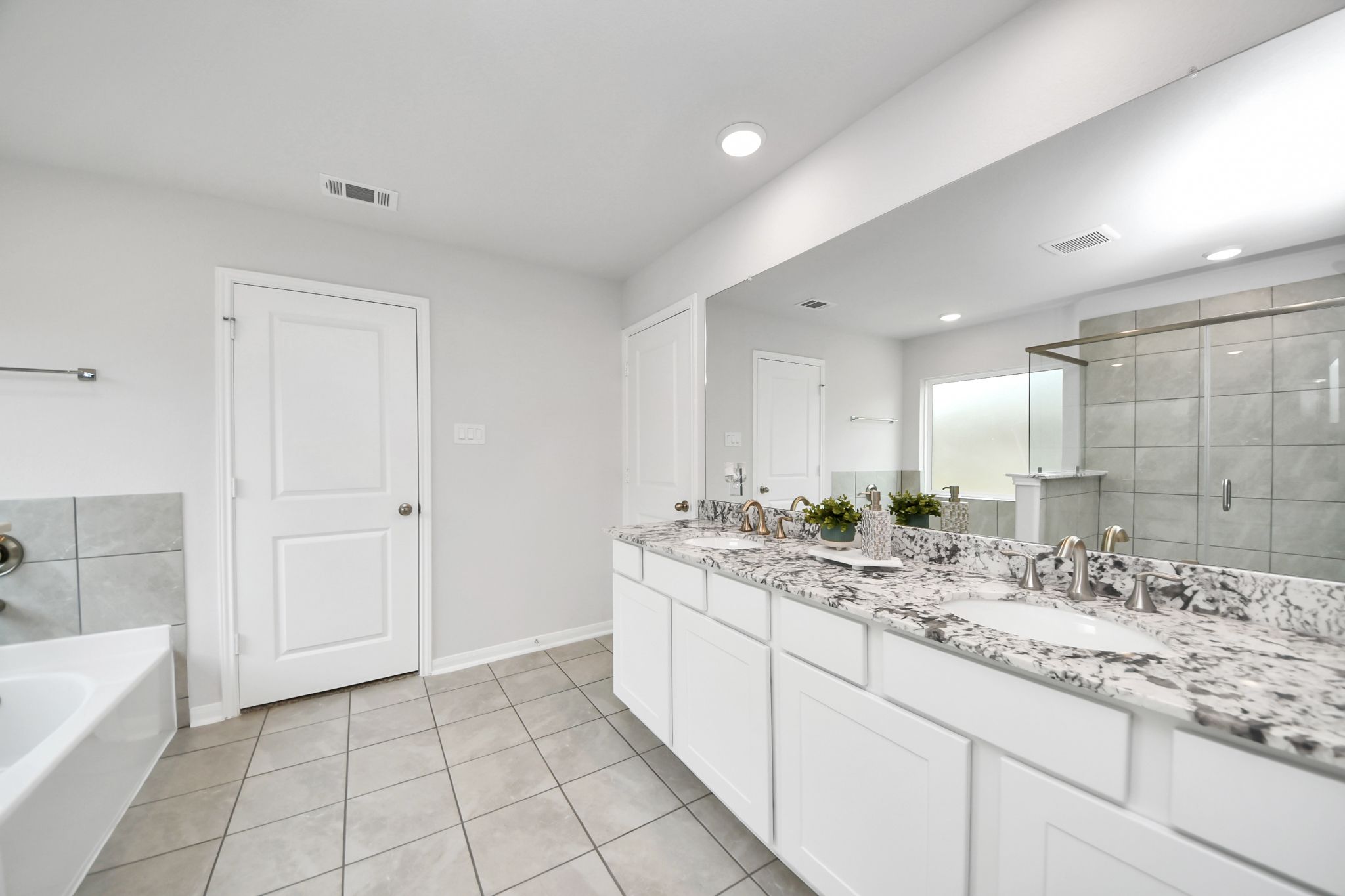 Primary bathroom with dual vanity, granite countertops, and tiled walk-in shower at Sunterra in Katy, TX by Davidson Homes.