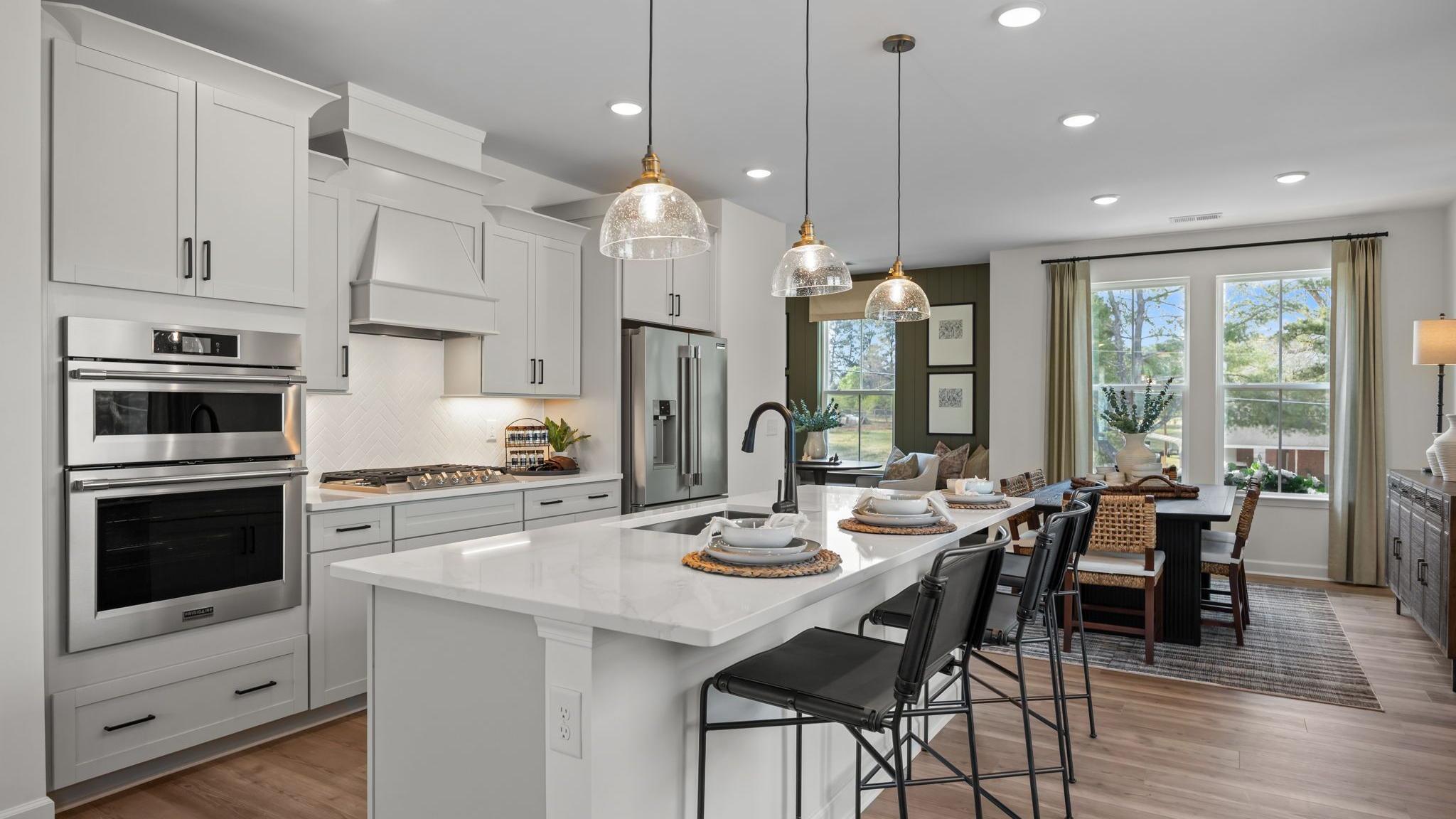 Spacious modern kitchen in Summers Walk Davidson NC with white cabinetry island seating stainless appliances hardwood floors