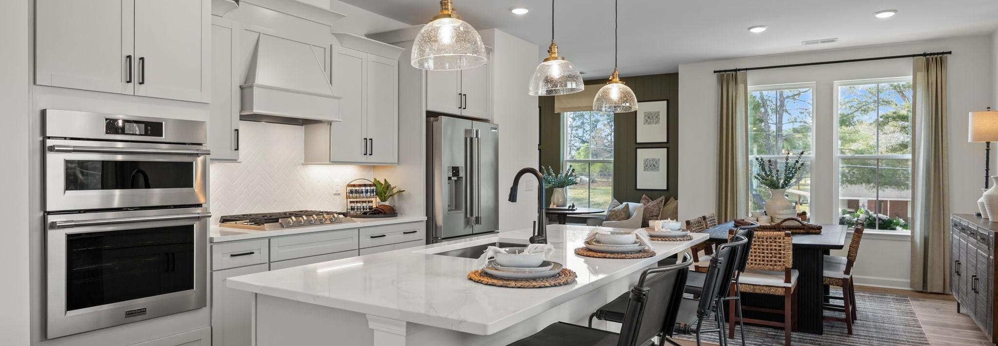 Spacious modern kitchen in Summers Walk Davidson NC with white cabinetry island seating stainless appliances hardwood floors