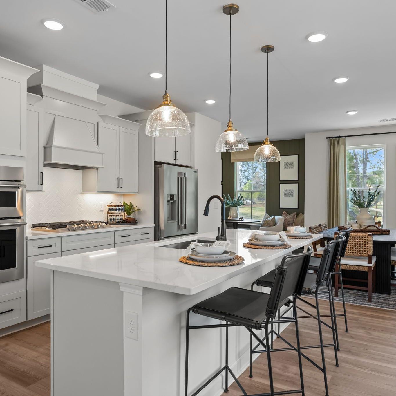 Spacious modern kitchen in Summers Walk Davidson NC with white cabinetry island seating stainless appliances hardwood floors