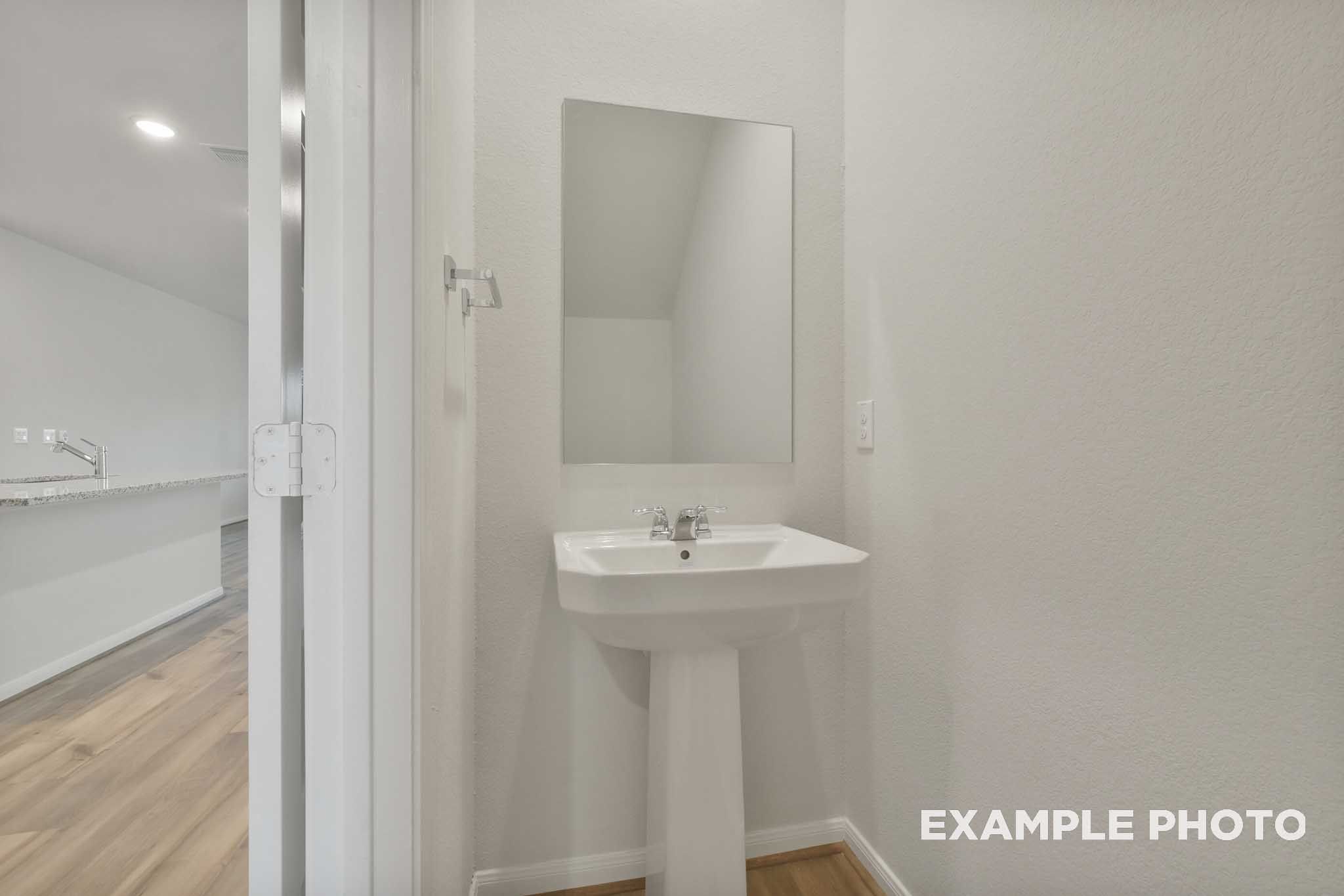 White pedestal sink with wall mirror in The Brazos half bath, Davidson Homes new construction in Beasley, Texas