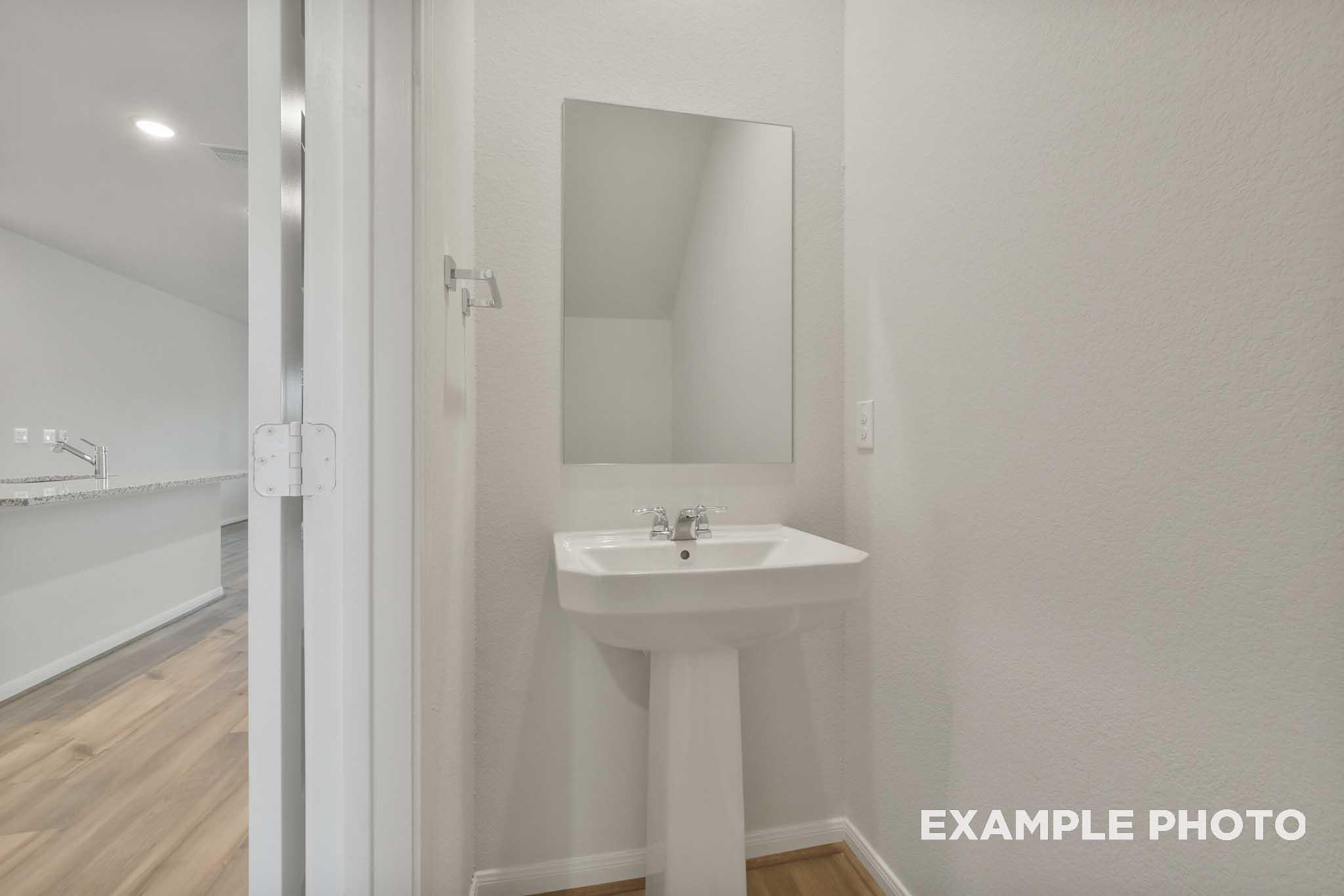 White pedestal sink with wall mirror in The Brazos half bath, Davidson Homes new construction in Beasley, Texas