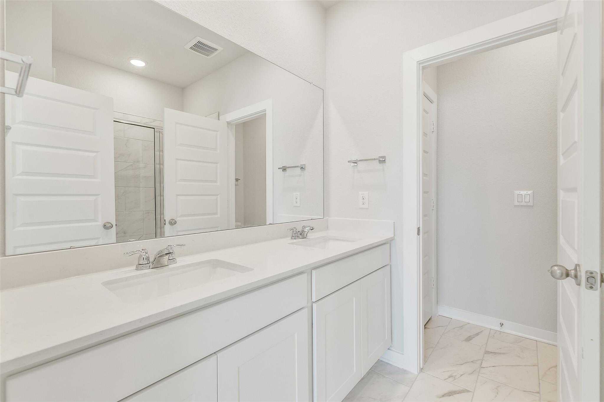 Modern master bathroom double vanity with white quartz counters and cabinets in Davidson Homes The Rio Grande H, Magnolia Texas