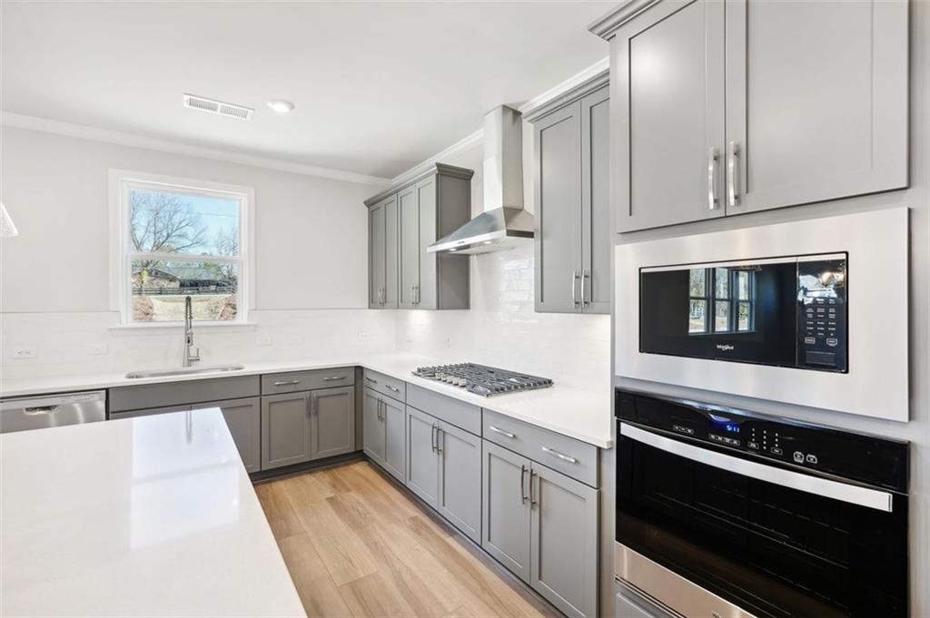 Modern kitchen with gray cabinets, quartz countertops, and stainless appliances in The Hickory C home, Wehunt Meadows.