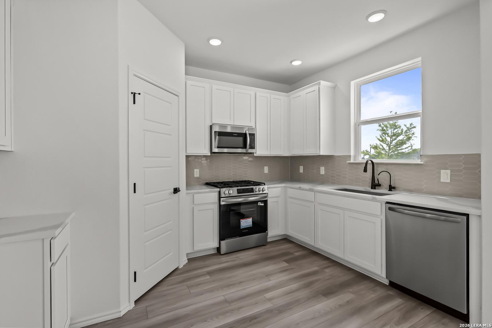 Modern kitchen with white cabinets, stainless steel appliances, and subway tile backsplash in The Florence B, San Antonio.