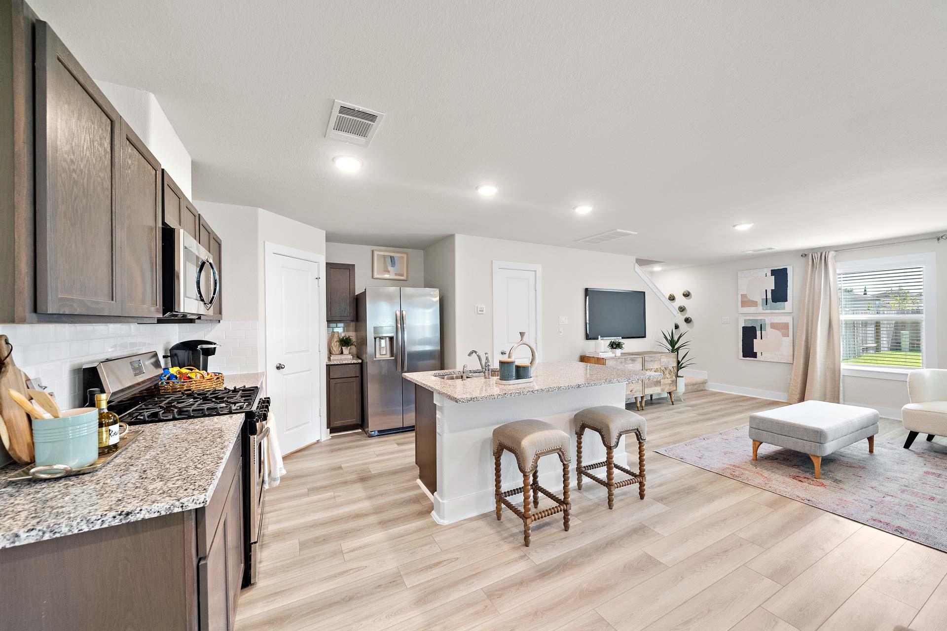 Modern open-concept kitchen at Haven at Kieth Harrow in Cypress TX by Davidson Homes with dark cabinets granite island and stainless appliances