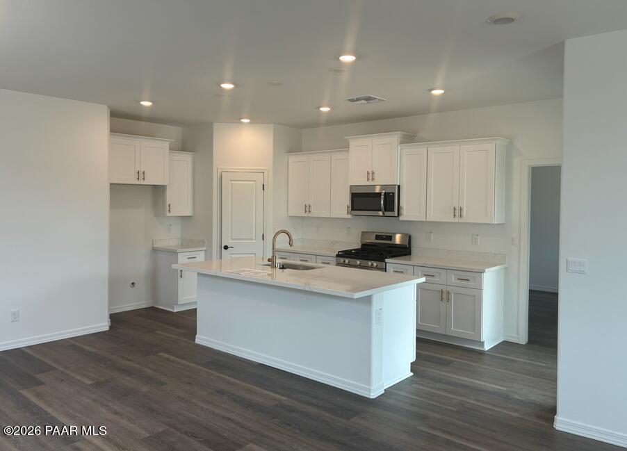 Modern white shaker kitchen with quartz island sink, stainless appliances, recessed lights, wood floors in Davidson Homes Malibu B, Prescott AZ