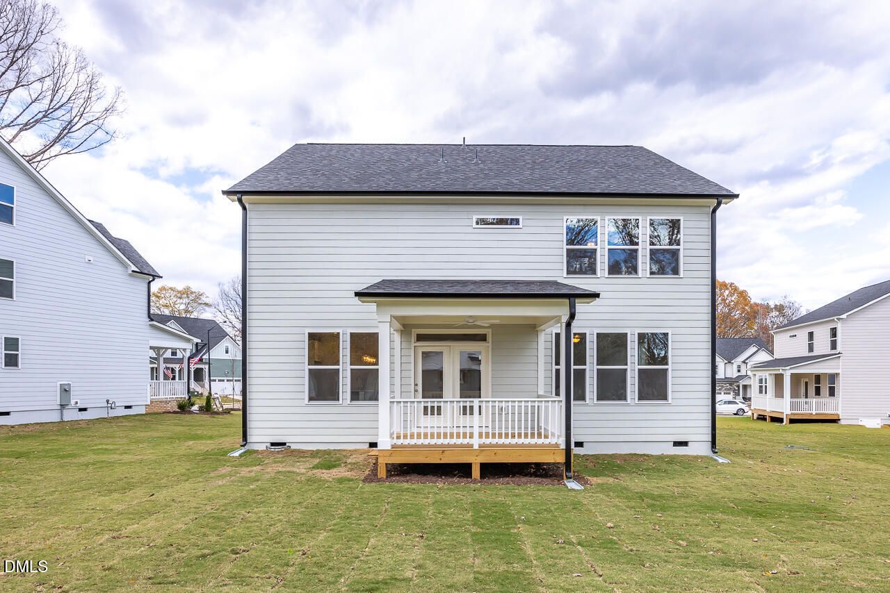 Two-story white Chestnut B home rear view with covered porch, deck, large windows, and green backyard in Lillington, NC