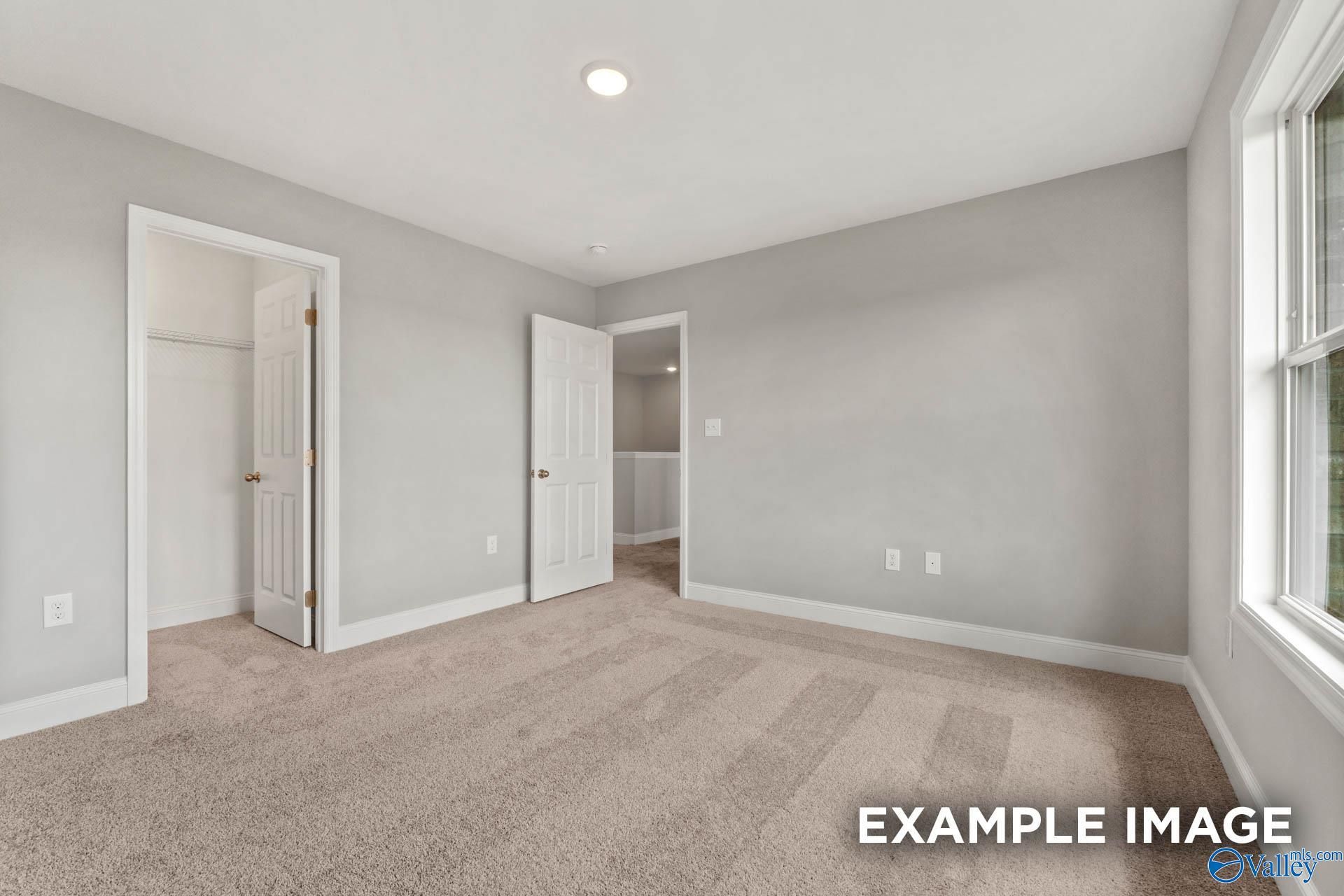 Bright secondary bedroom with gray walls, neutral carpet, double closet doors, bath access, and large window in Davidson Homes Shelby B, Athens AL