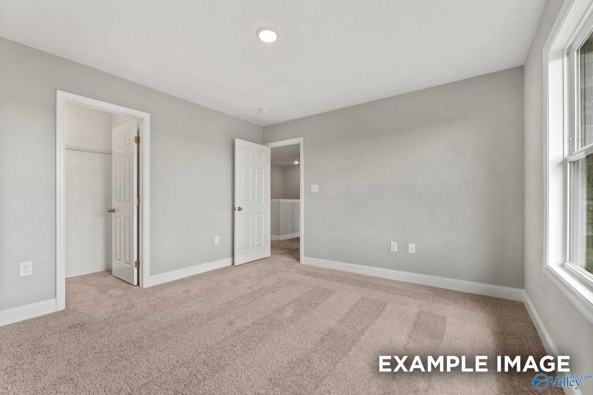 Bright secondary bedroom with gray walls, neutral carpet, double closet doors, bath access, and large window in Davidson Homes Shelby B, Athens AL