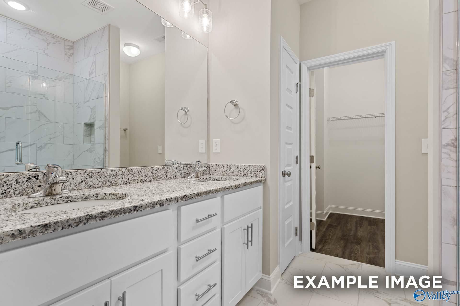 Elegant master bathroom with double vanity, marble shower, and walk-in closet in Davidson Homes The Camilla A, Hartselle, Alabama