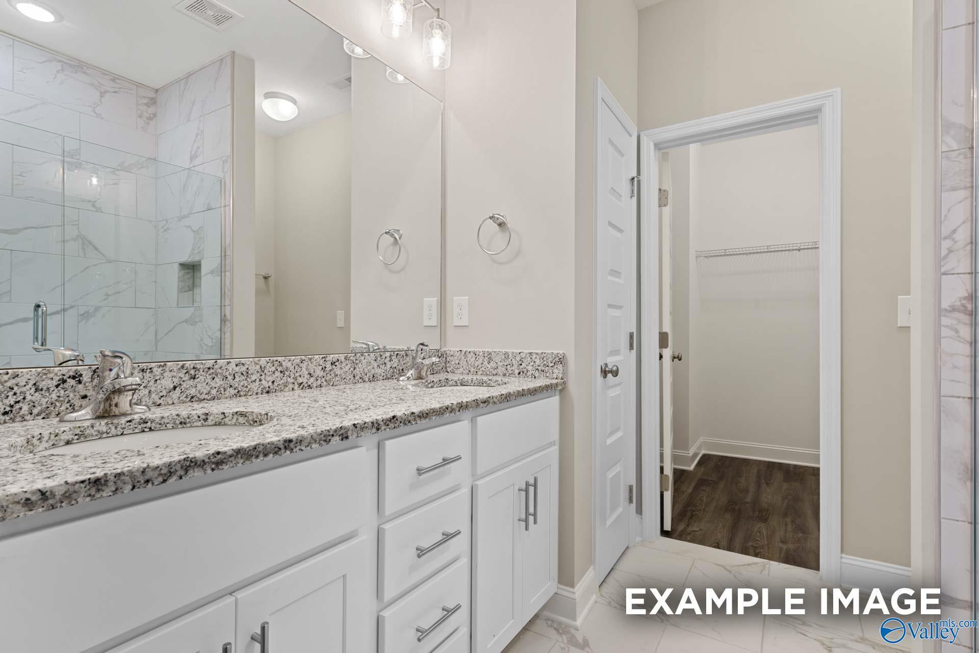 Elegant master bathroom with double vanity, marble shower, and walk-in closet in Davidson Homes The Camilla A, Hartselle, Alabama