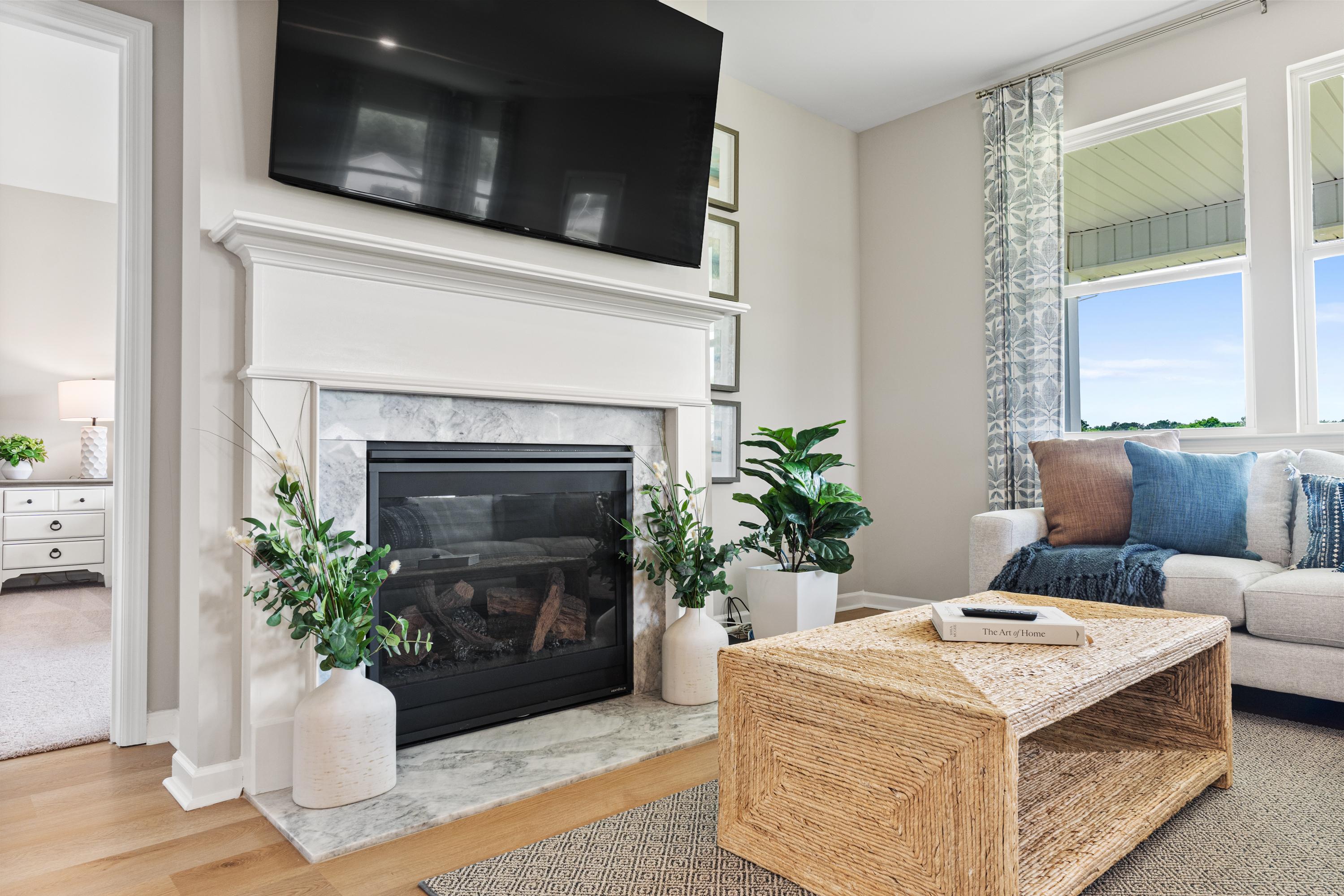 Cozy living room at Forest Glen in Hazel Green, Alabama featuring white marble fireplace, mounted TV, beige sofa, and potted plants