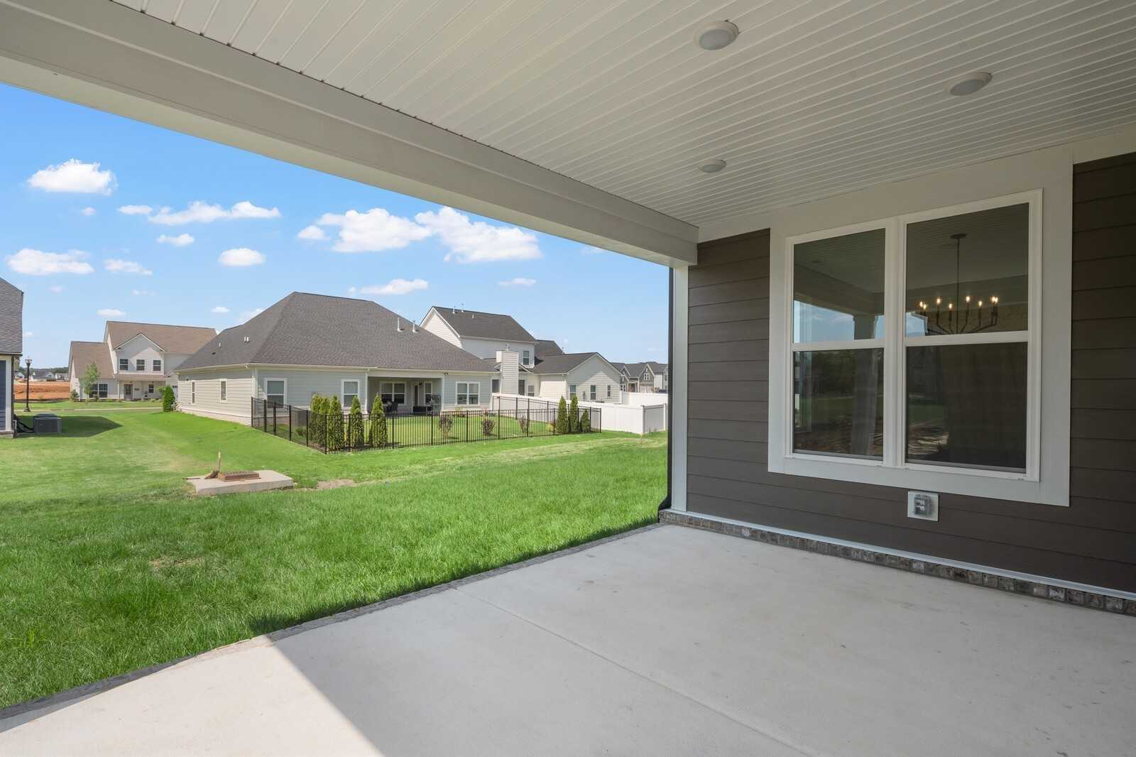 Covered patio with recessed lights overlooking lush green backyard and neighboring homes in Shelton Square, Murfreesboro, Tennessee