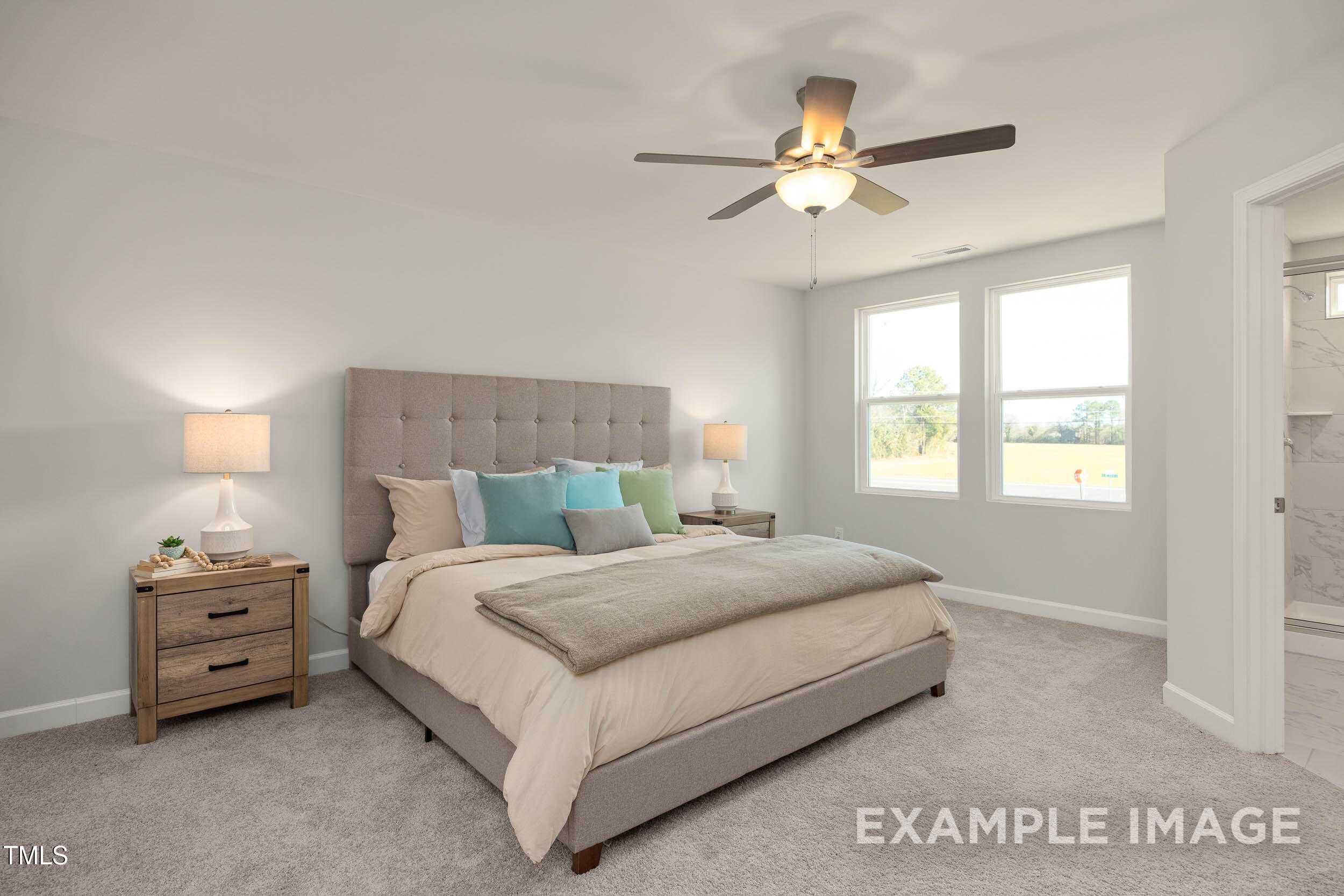 Cozy master bedroom with tufted gray headboard king bed, ceiling fan, and en-suite bath in Davidson Homes The Graham, Fuquay-Varina, NC