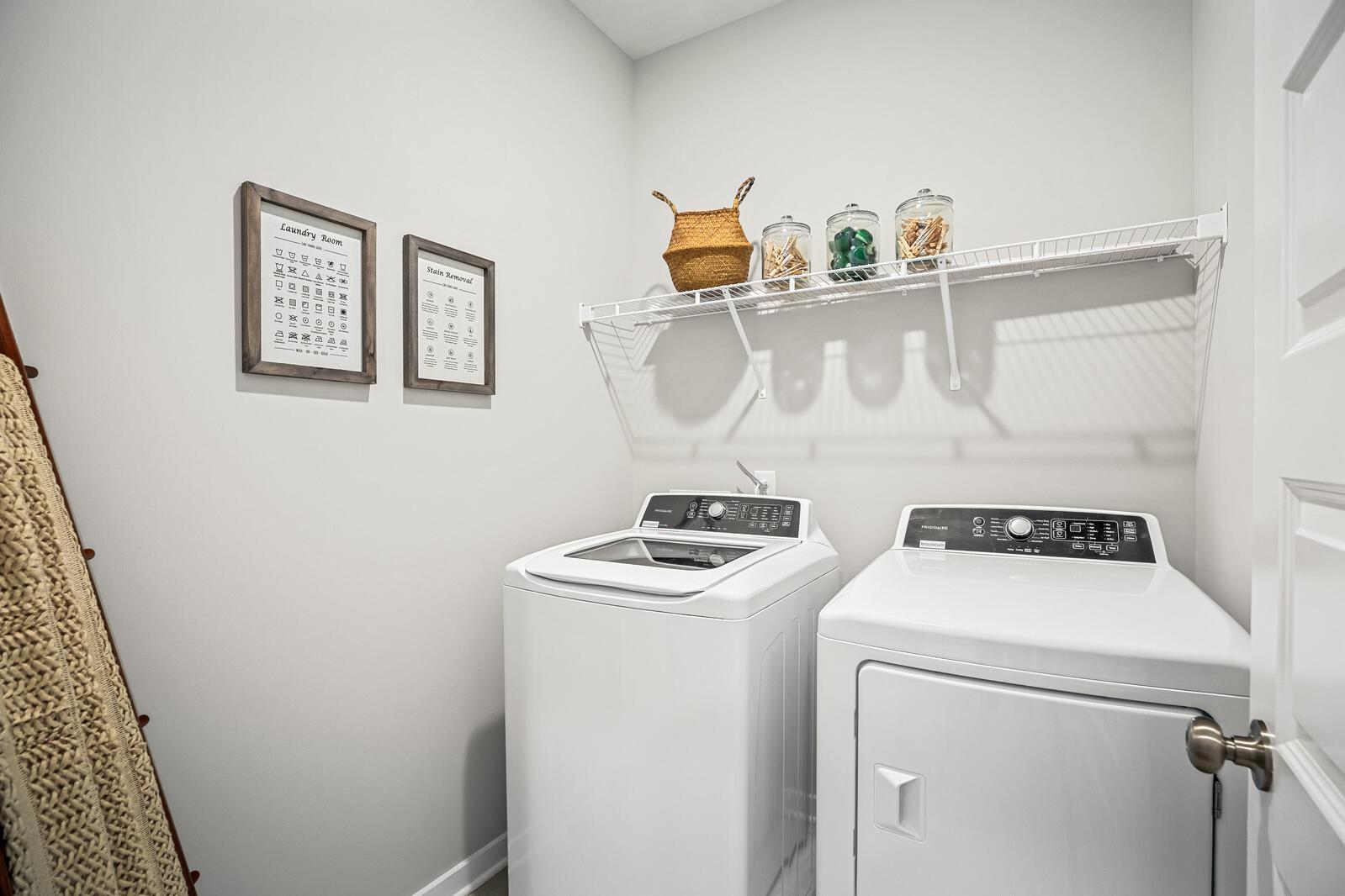 Spacious laundry room at Sage Farms in White House Tennessee with white washer dryer wire shelving and decorative baskets