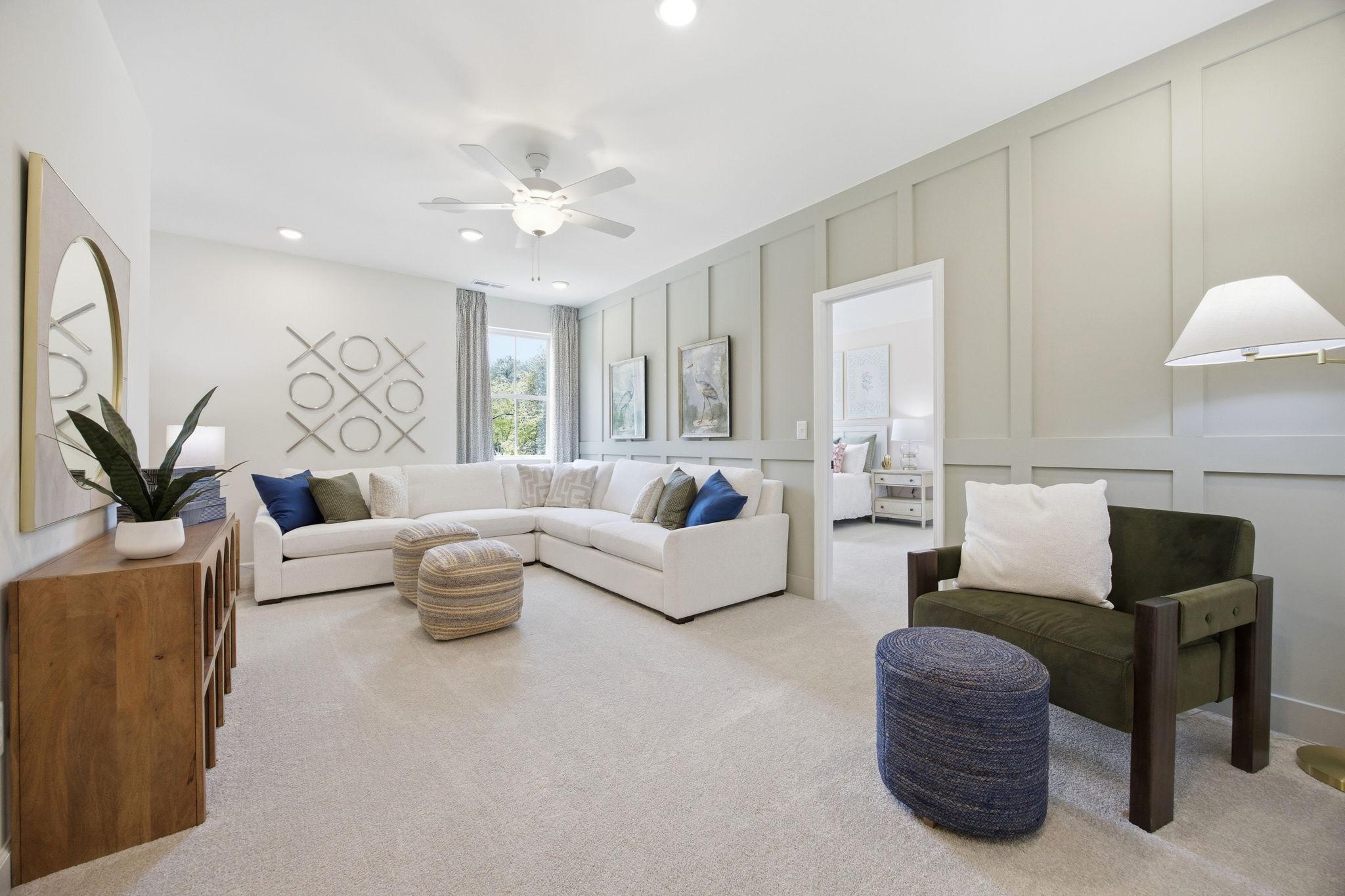Spacious living area in The Ashport featuring an L-shaped sectional, board and batten walls, and main floor suite access.