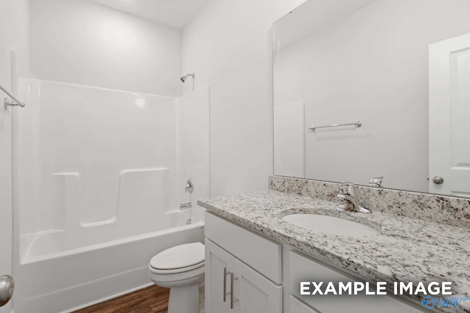Modern bathroom with granite vanity, tub-shower combo, white tiles, and hardwood floors in Davidson Homes Asheville C, Meridianville, AL