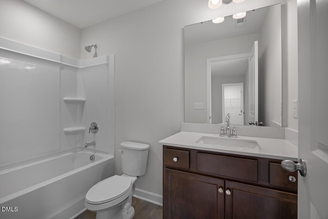 Modern bathroom with dark wood vanity, white countertop, and tub-shower combo in The Hickory II B at Wellers Knoll.
