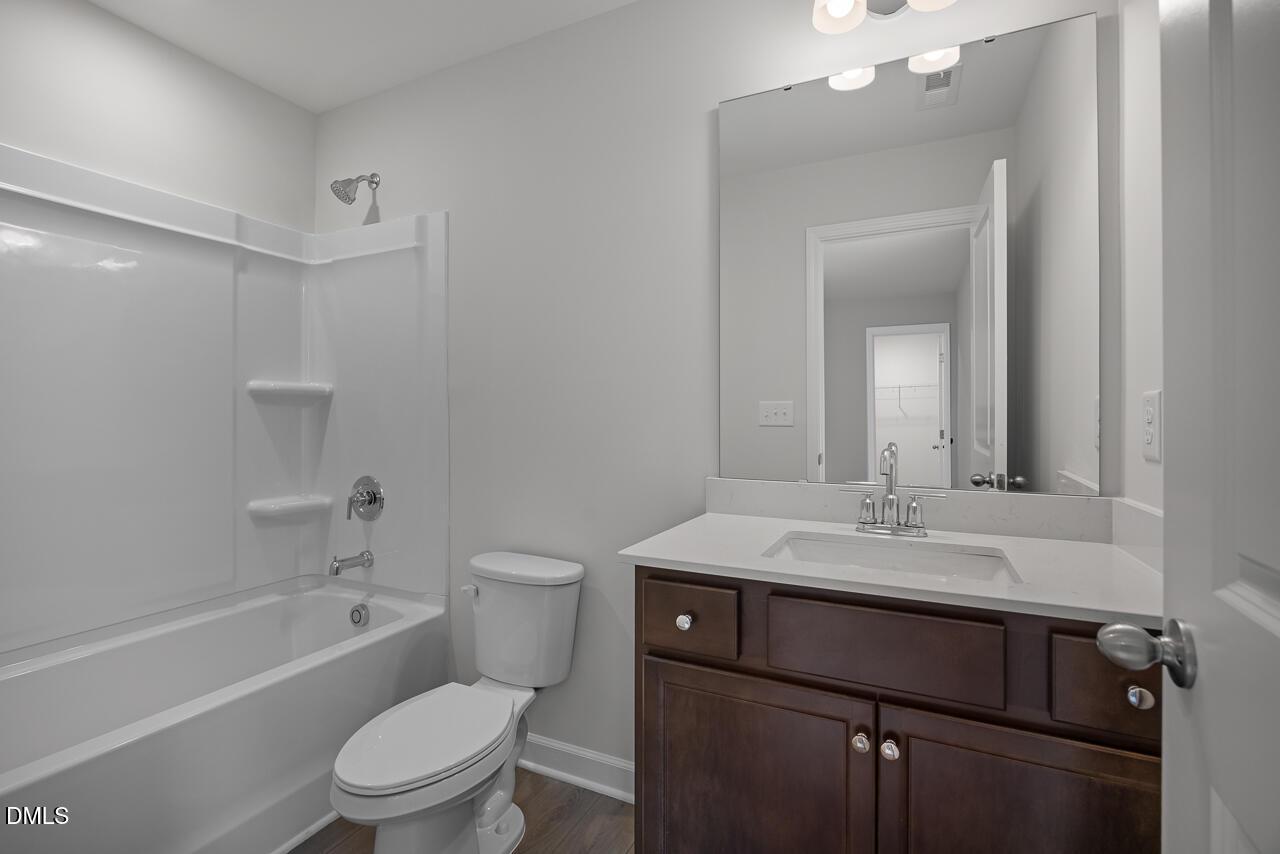 Modern bathroom with dark wood vanity, white countertop, and tub-shower combo in The Hickory II B at Wellers Knoll.